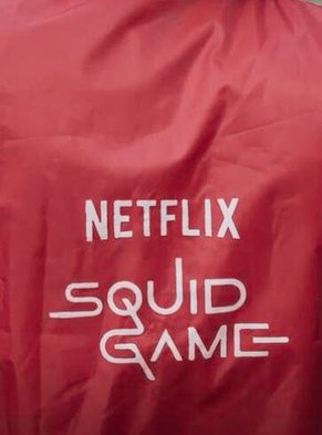 A red Netflix Squid Game rider jersey worn on a Zepto delivery run